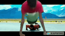 a man is doing push ups on a road with mountains in the background