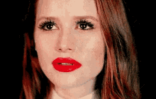 a close up of a woman 's face with red lipstick on her lips .