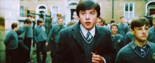 a group of boys in school uniforms are walking down the street .