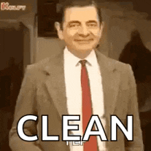 mr bean is wearing a suit and tie and smiling while saying clean .