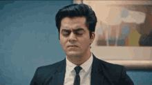 a man in a suit and tie is looking down with his eyes closed .