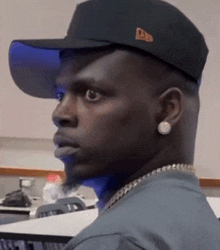 a man wearing a hat and earring looks to the side