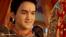 a boy with a red dot on his forehead looks at a woman in a sony television show