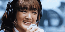 a woman wearing headphones is smiling and holding a microphone in her hand