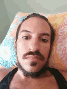 a man with a beard and mustache is laying on a pillow