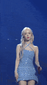 a woman in a blue dress is singing into a microphone on a stage