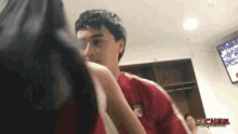 a man in a red shirt is standing next to a woman in a locker room with the words mychas on the bottom right