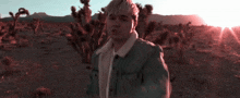 a man is standing in a desert with the sun shining through the trees