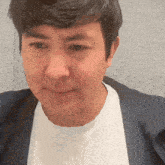 a man wearing a white shirt and a blue jacket making a funny face