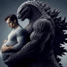 a man is holding a pregnant belly next to a large monster .