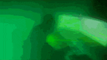 a person is using a laptop in a dark room with a green light behind them