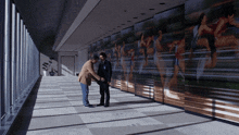 two men shaking hands in a hallway with a large painting on the wall
