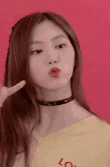 a young woman wearing a choker and a yellow shirt is making a face .