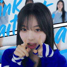 a girl in a blue and white striped sweater is giving a thumbs up sign