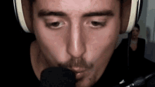 a man with a mustache is talking into a microphone while wearing headphones .