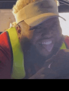 a man wearing a visor and a safety vest is smiling