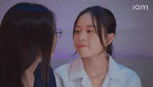 two women are looking at each other with the iqyi logo behind them