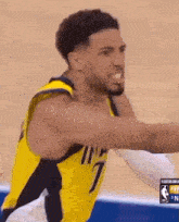 a basketball player in a yellow jersey is reaching out to catch a basketball .