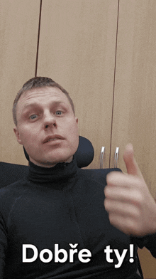 a man giving a thumbs up with the words ' dobre ty ' behind him