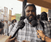 a man wearing a plaid shirt is being interviewed by someone with a microphone that says premiere on it