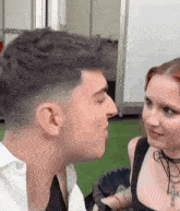 a man is kissing a woman on the cheek while standing next to her .