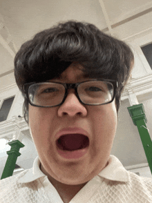 a man wearing glasses and a white shirt making a funny face