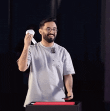 a man in a gray shirt is holding a white object in his hand