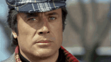 a close up of a man wearing a plaid hat and scarf