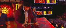 a man in a suit is holding a wrestling championship belt while walking on a stage .