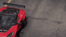 a red sports car with a black and red stripe on the hood is driving down the road