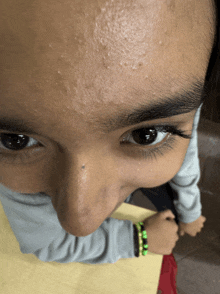 a close up of a person 's face with a green bracelet on her wrist