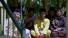 a group of people are sitting on a porch and the word mantaka is on the bottom right