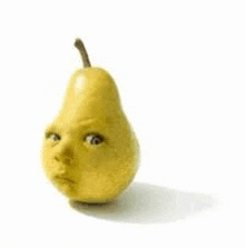 a pear with a baby 's face on it is sitting on a white surface .