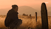 a woman kneeling in front of a grave that says joel miller on it