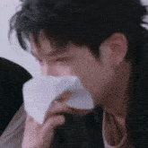 a close up of a person blowing their nose with a tissue .
