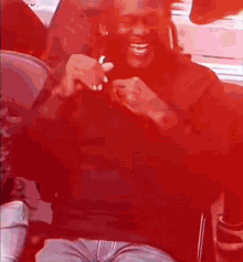 a man in a red shirt is sitting on a red chair and smiling