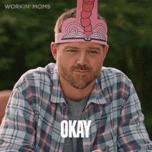 a man in a plaid shirt is wearing a paper hat with the word okay on it
