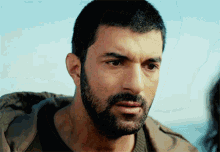 a close up of a man with a beard looking at the camera