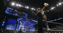a woman in a wrestling ring holds up a trophy with the word all elite wrestling on the screen behind her