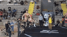 a wrestler is jumping in the air in front of a banner that says #threat level noon