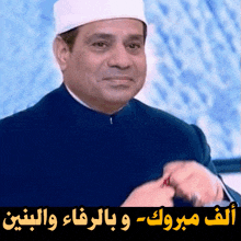 a man wearing a white hat and a blue jacket with arabic writing on the bottom