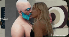 a man with a blue mask on his face kisses a woman on the cheek