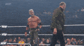 a man with a beard is standing in a boxing ring talking to another man .