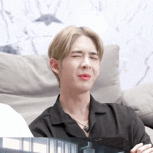 a man sitting on a couch making a funny face with his eyes closed