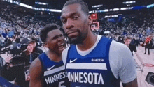 two minnesota basketball players are standing on the court during a game .