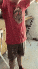 a person in a red shirt and shorts is standing in a room with their arms outstretched .