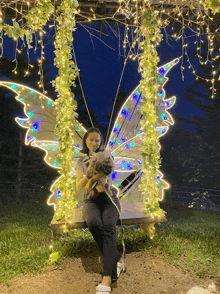 a woman holding a dog on a swing with wings