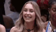 a woman is smiling in a crowd of people while sitting in a chair .