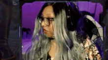 a woman with glasses and gray hair is sitting in front of a computer monitor .