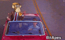 a man in a suit is driving a red car with a monkey head on the roof